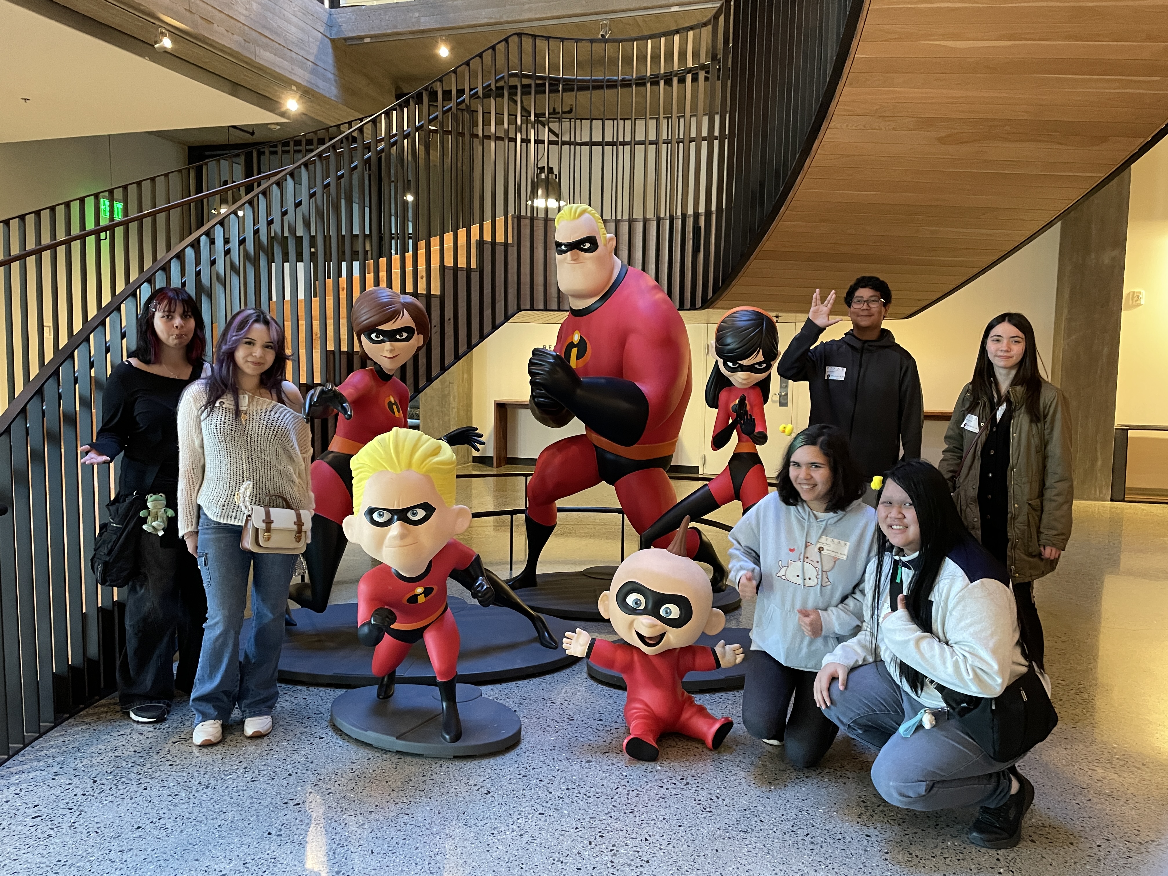 REEL students posing with The Incredibles sculptures during a field trip to Pixar Animation Studios